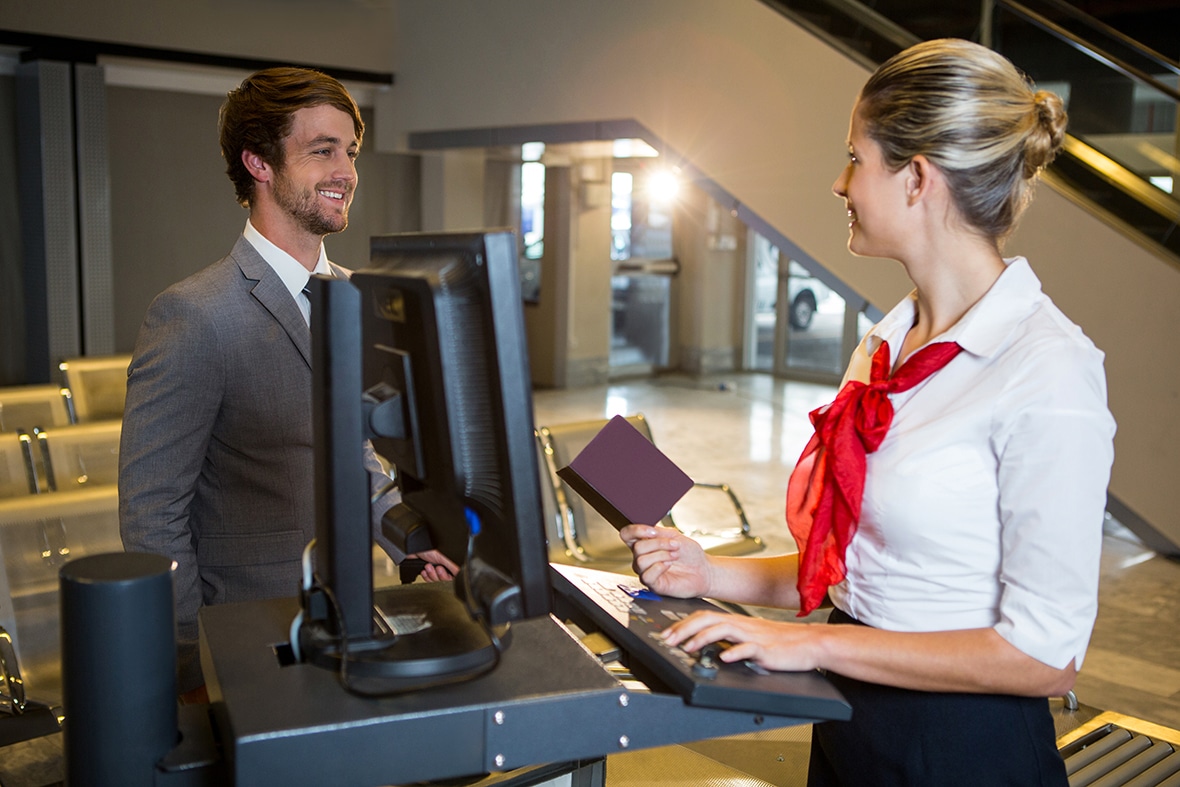 Businessman interacting with female airport staff at the check in desk in airport terminal