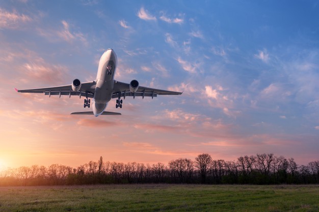 beautiful-airplane-landscape-with-big-white-passenger-airplane-is-flying-blue-sky-with-clouds-green-grass-field-summer_159067-652